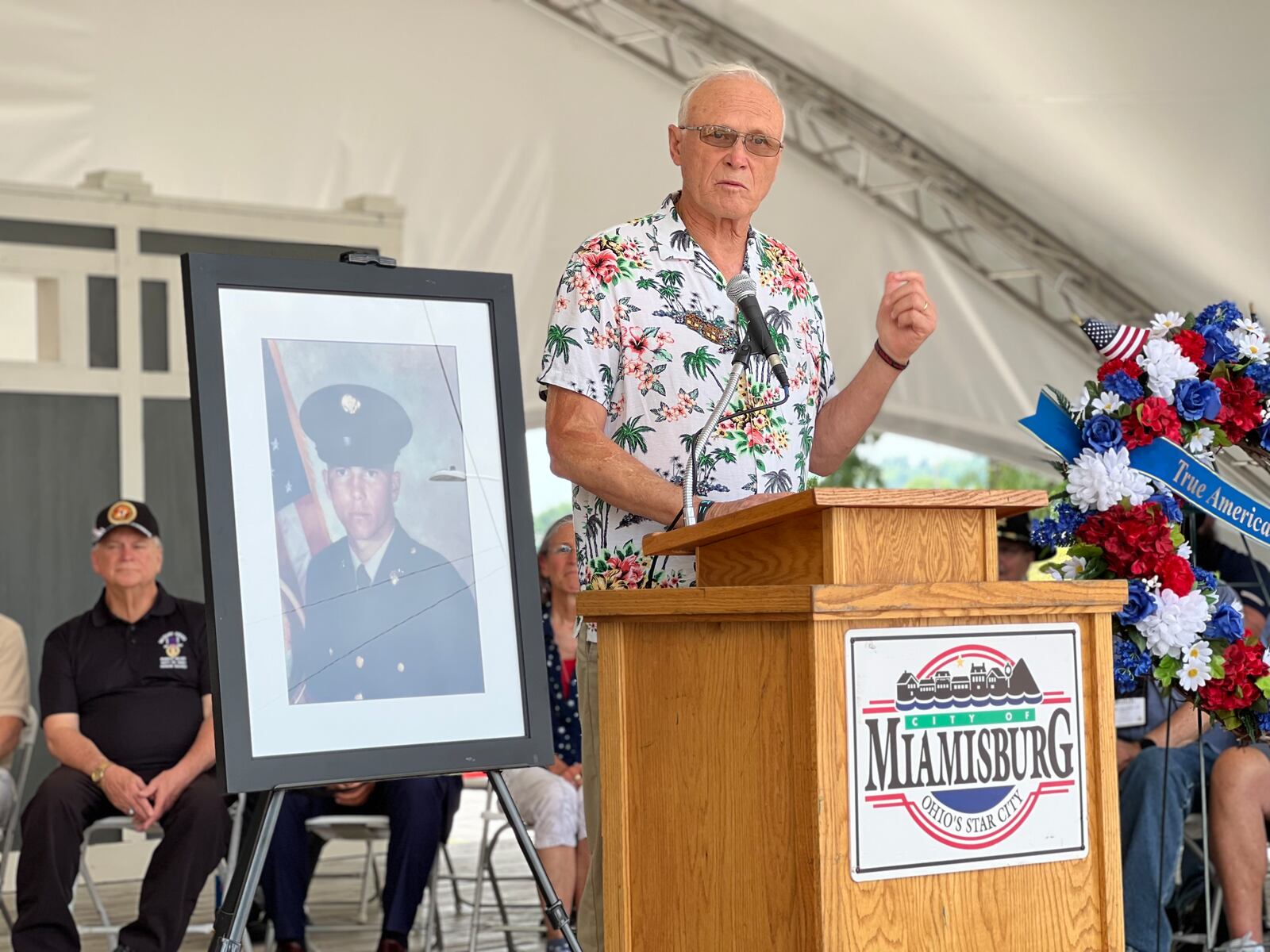 Jim Skaggs spoke Saturday at the road dedication ceremony honoring Sgt. Gary McKiddy, whose photo sits left. AIMEE HANCOCK/STAFF