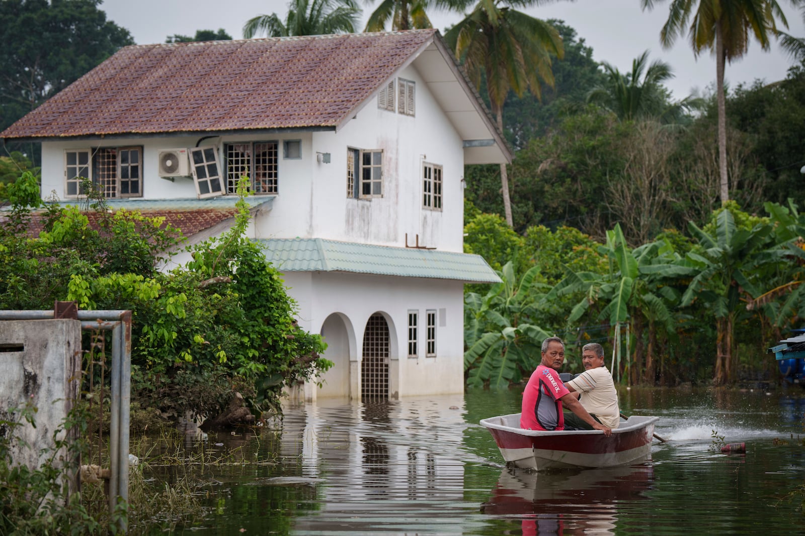 People use a boat to cross a flooded area in Tumpat, Tumpat, outskirts of Kota Bahru, Malaysia, Tuesday, Dec. 3, 2024. (AP Photo/Vincent Thian)