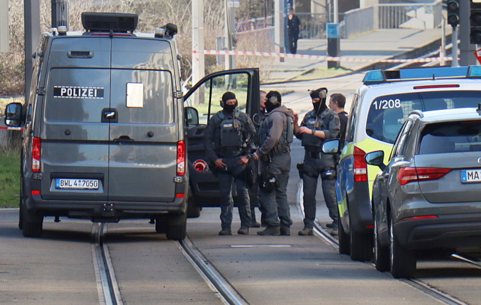 Officers from the police defusing service stand near a damaged vehicle in front of an access road to the Rhine bridge, in Mannheim, Germany, Monday March 3, 2025, following an incident in which one person was killed and others injured when a car rammed into a crowd, German police said. (Boris Roessler/dpa via AP)