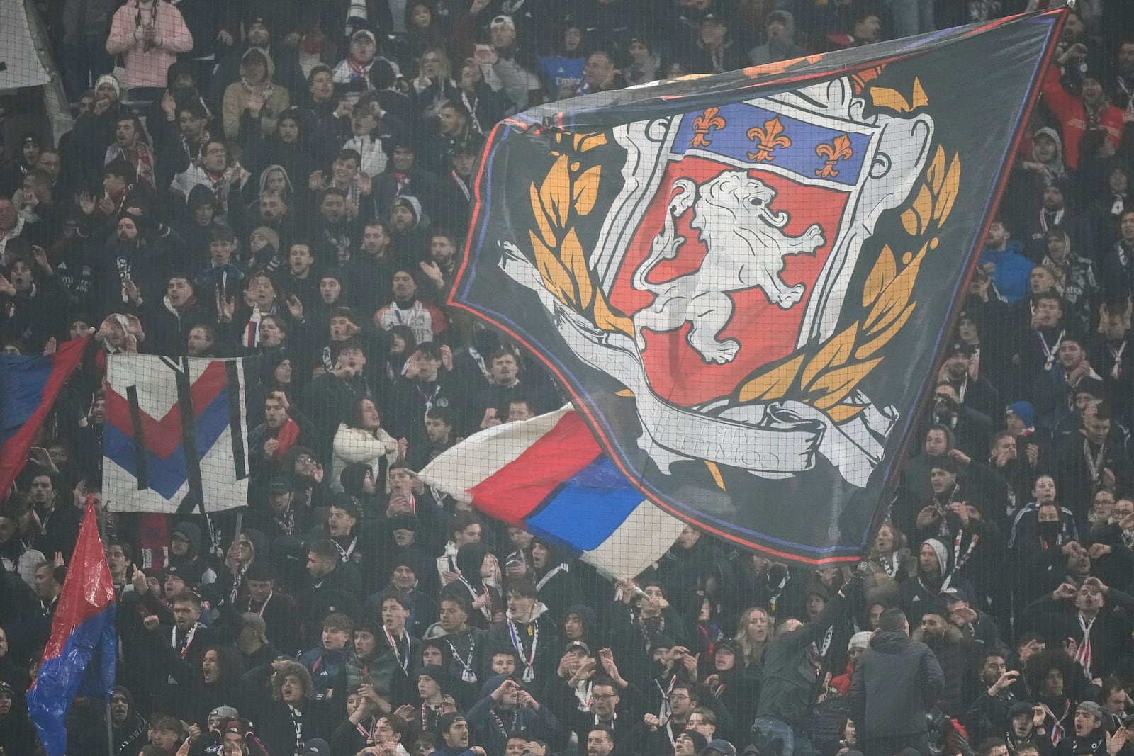 Lyon' supporters hold a giant flag during the Europa League soccer soccer match between Lyon and Eintracht Frankfurt at Decines stadium outside Lyon, France, Thursday, Dec. 12, 2024. (AP Photo/Michel Euler)