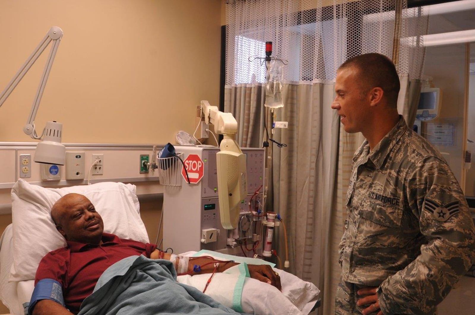 Senior Airman Jason Scoles, a dialysis technician with the 88th Medical Group, checks on his patient John Pennix as Pennix is receiving his dialysis treatment at the Wright-Patterson Medical Center. Patients go on dialysis when the kidneys are no longer able to filter and clean blood on its own. (U.S. Air Force photo/Stacey Geiger)