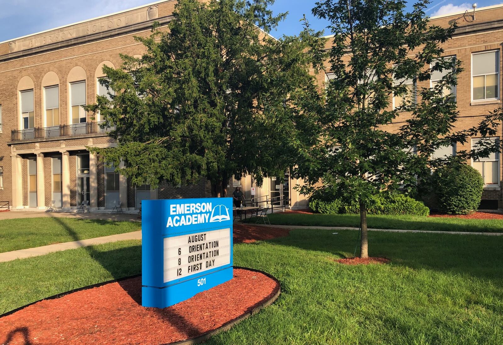 Emerson Academy staff begin to set up tables and chairs outside the front door on the first day of online classes Wednesday, Aug. 12, 2020. Parents who came to school to fill out paperwork were encouraged to maintain social distancing outside until their turn in the office.