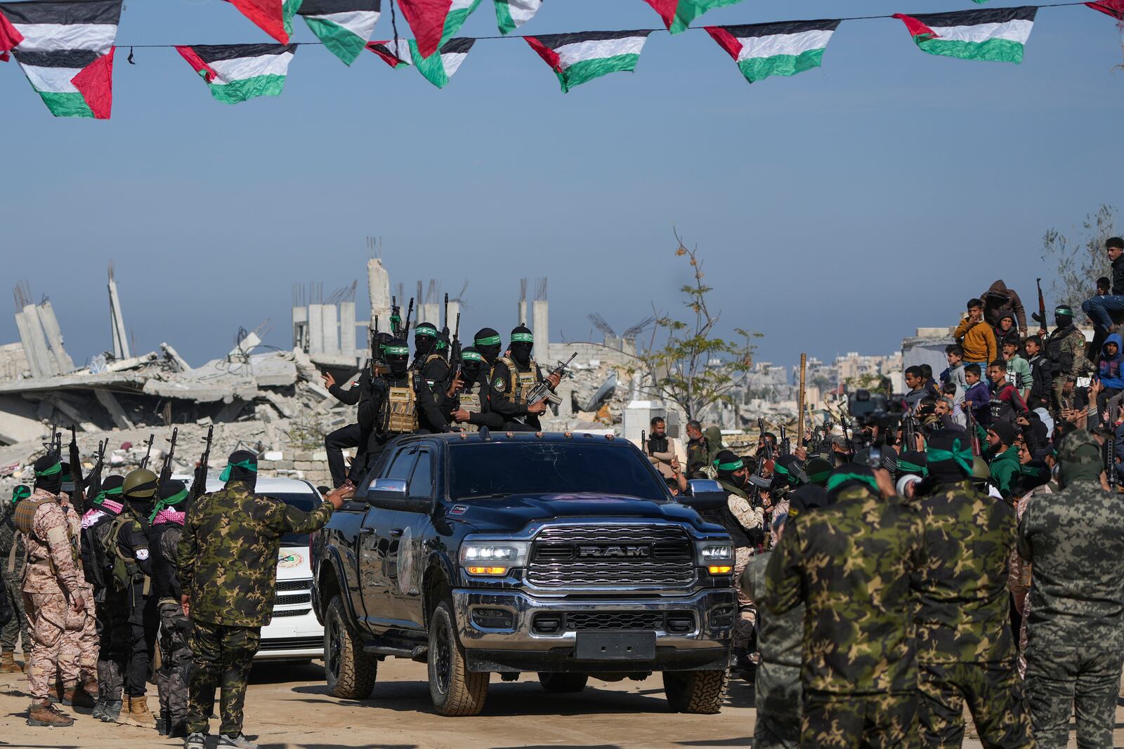 Hamas fighters arrive on a pick-up truck for the hand over of captives Iair Horn, Alexander Troufanov, and Sagui Dekel Chen to the Red Cross in Khan Younis, Gaza Strip, Saturday, Feb. 15, 2025. (AP Photo/Abdel Kareem Hana)