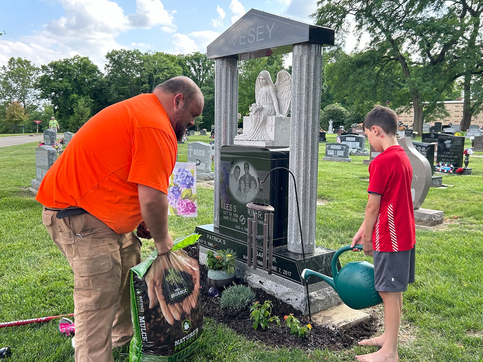 Vesey's son, Patrick Vesey (L) and grandson Warren planting flowers at the gravesite of Sarah and her dad Les. The pair often do things together to help them remember their lost family members.