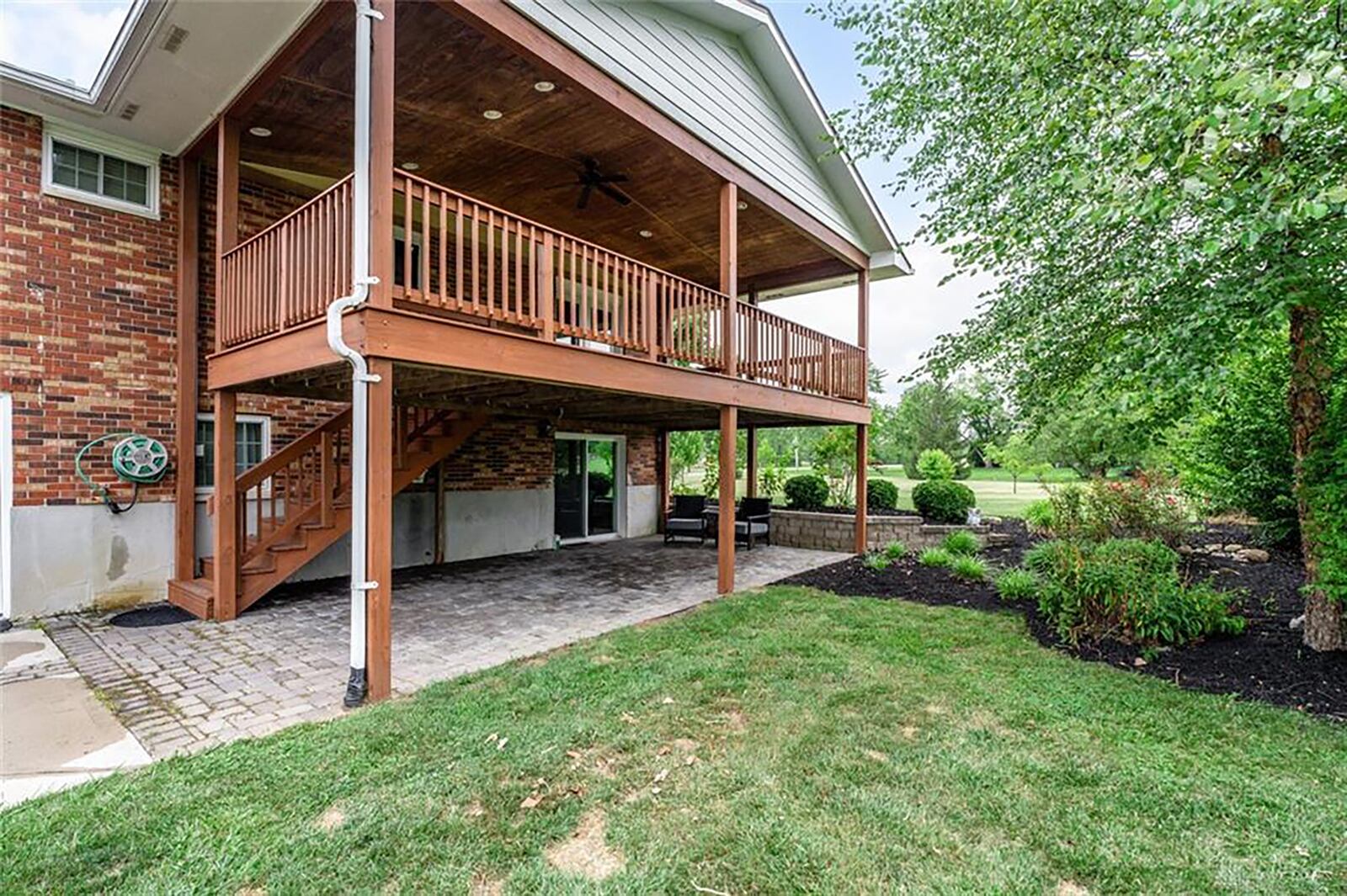 The rear of the home has a walk out lower level with a paver patio and an upper level 12x28 wood deck with railings and a ceiling fan.