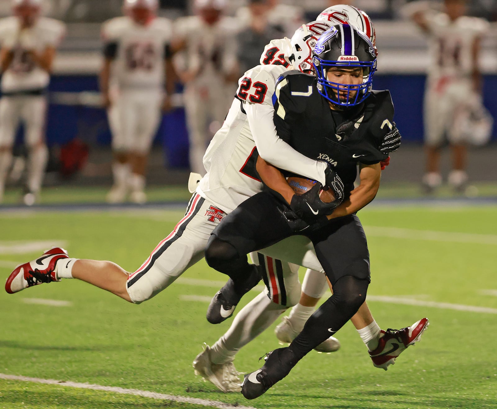 Xenia's Shawn Fishwick is tackled by Tipp's Max Deckard during Friday's game. BILL LACKEY/STAFF