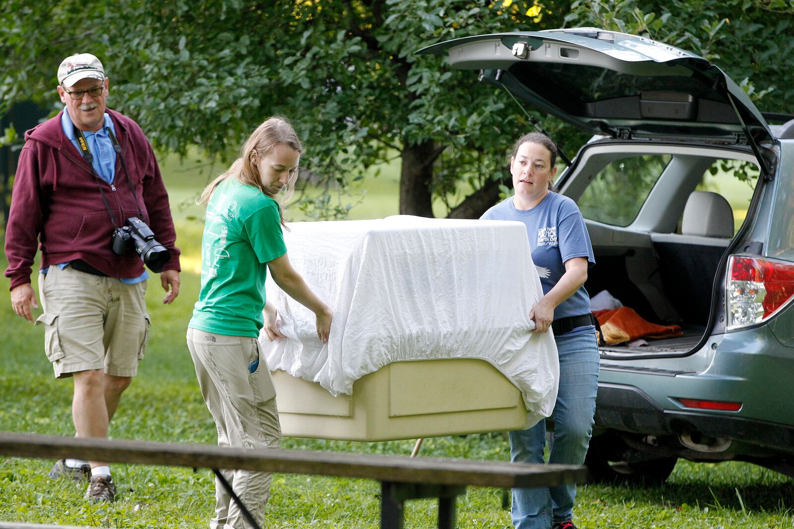 Rebecca Jaramillo (right), director of the Glen Helen Raptor Center and Rachel Hammond (left) an assistant, carry an extra large pet container with Prairie, a juvenile bald eagle inside.  At rear is Jim Weller, the founder of Eastwood Eagle Watchers. The eagle was released back into Carillon Historical Park Tuesday morning after 12-days of strengthening and rehabilitation. LISA POWELL / STAFF