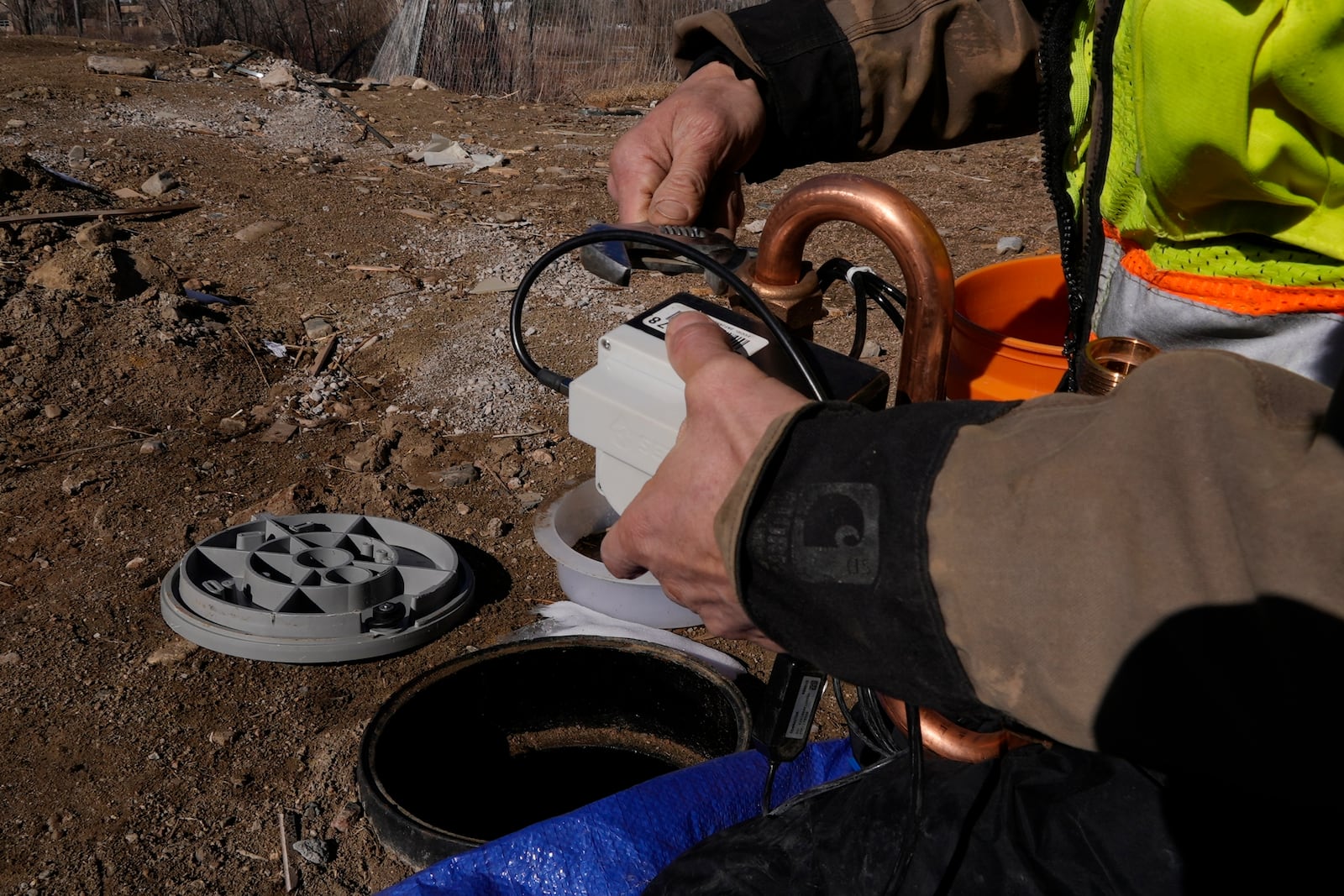 A technician installs a new water meter with a remote shutoff valve Thursday, Feb. 13, 2025, in Louisville, Colo. (AP Photo/Brittany Peterson)