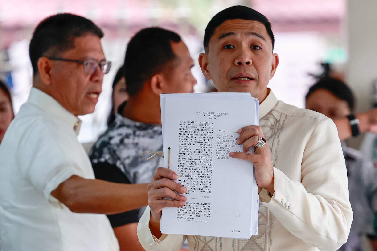 Philippine Vice President Sara Duterte's lawyer Israelito Torreon, right, shows documents they filed asking the 15-member high court to annul her impeachment and block the trial at the Supreme Court in Manila, Philippines Tuesday, Feb. 18, 2025. (AP Photo/Gerard Carreon)