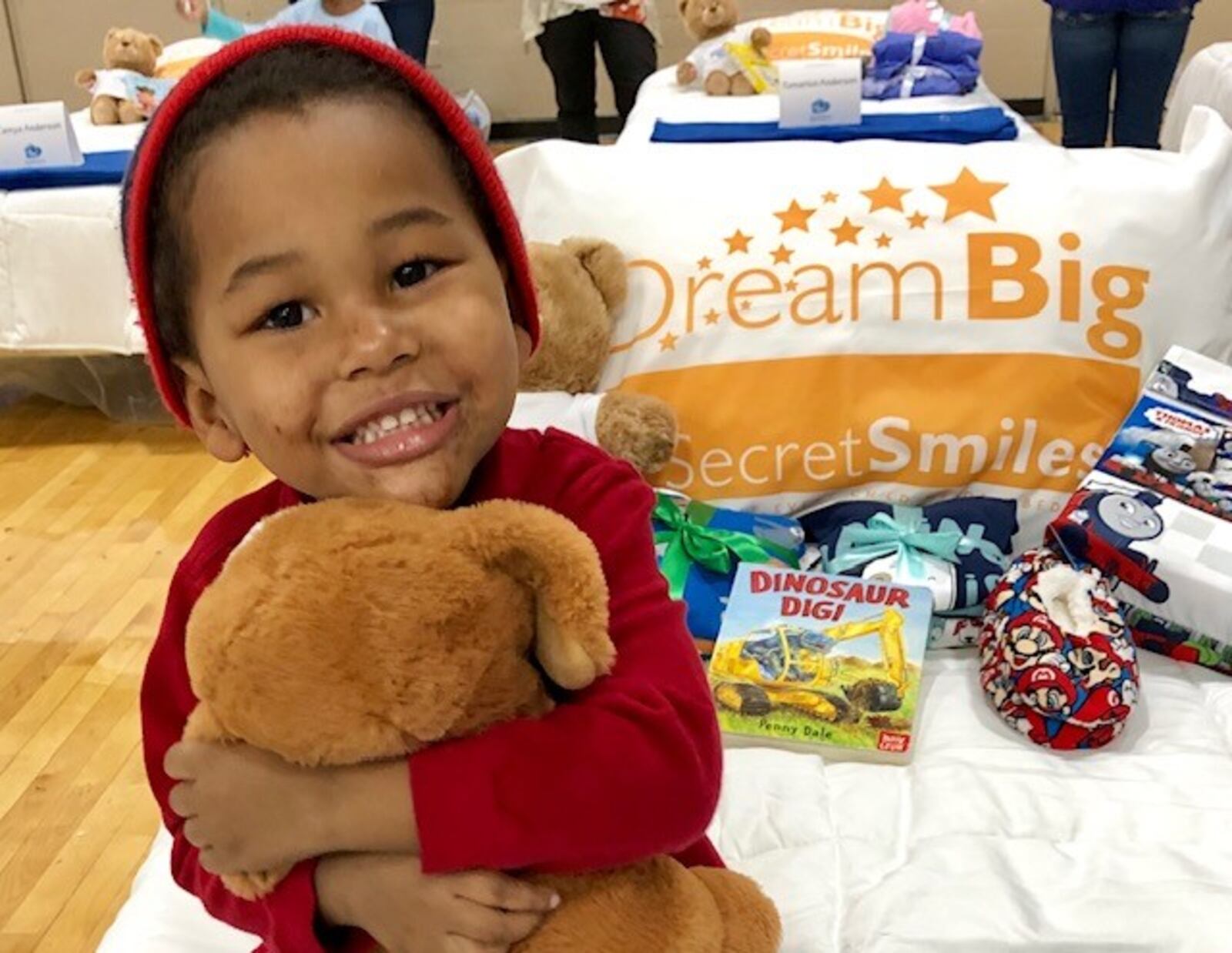 In a Secret Smiles promotional photo, a happy child sits on his new bed at one of the organizations “Day to Dream: events at the Frericks Center  on the UD campus. CONTRIBUTED