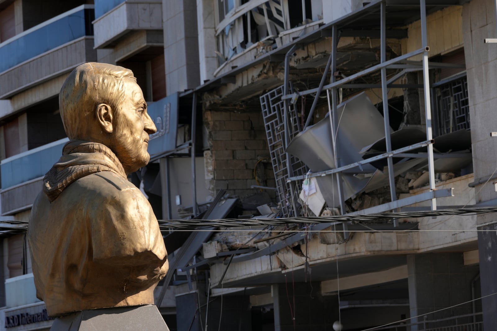 A bust of late Iranian General Qassem Soleimani, stands in front of a destroyed branch of the Hezbollah-run Qard al-Hassan which was hit by an Israeli airstrike in Dahiyeh, Beirut, Lebanon, Monday, Oct. 21, 2024. (AP Photo/Hussein Malla)