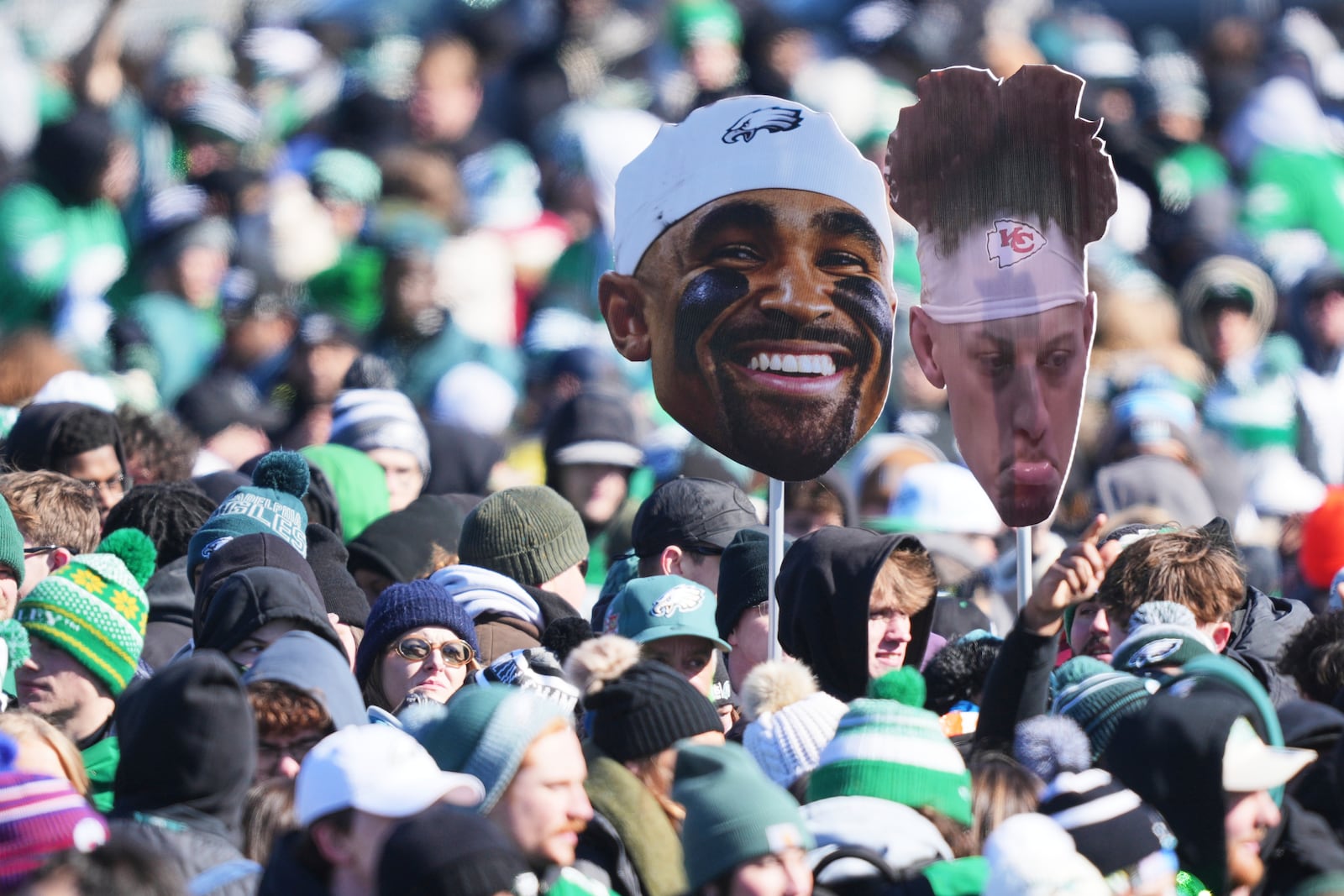 Fans hold up a cutout of a smiling Philadelphia Eagles quarterback Jalen Hurts, center, and a frowning Kansas City Chiefs quarterback Patrick Mahomes during the Eagles' NFL football Super Bowl 59 parade and celebration, Friday, Feb. 14, 2025, in Philadelphia. (AP Photo/Matt Rourke)