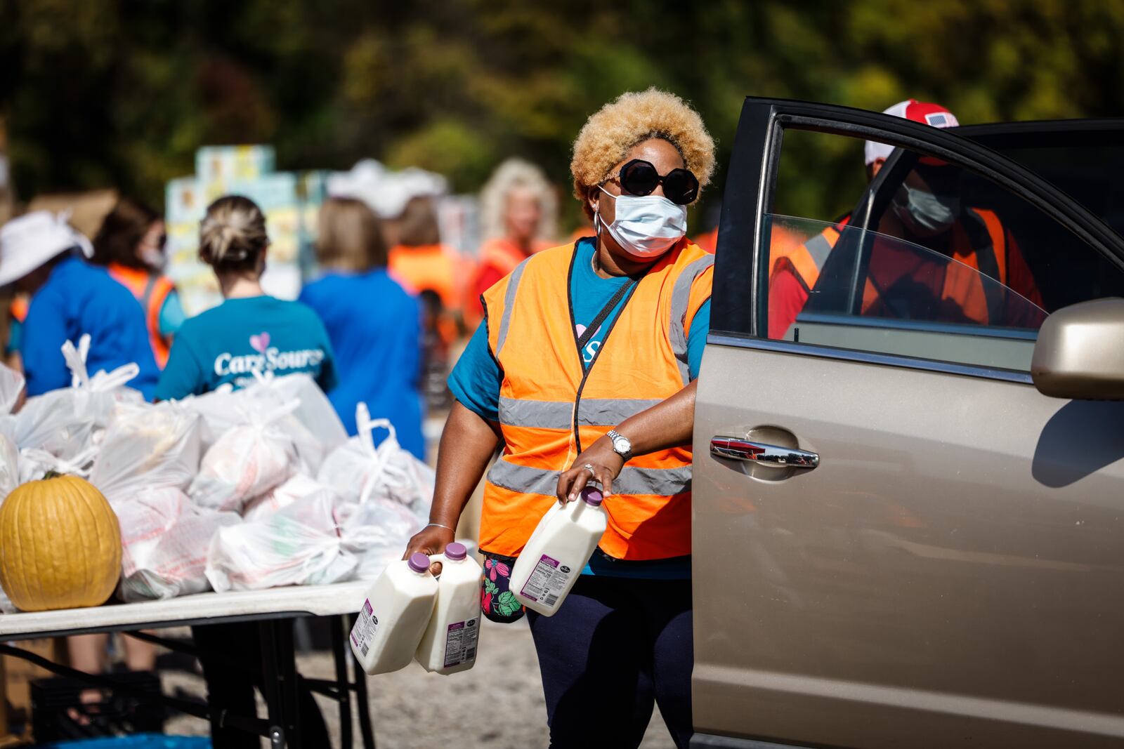 Workers and volunteers bring food to vehicles lined up at The Foodbank Inc.'s mass food distribution Thursday, Sept. 30, 2021, at the Dixie Twin Drive-In in Harrison Twp. STAFF / JIM NOELKER