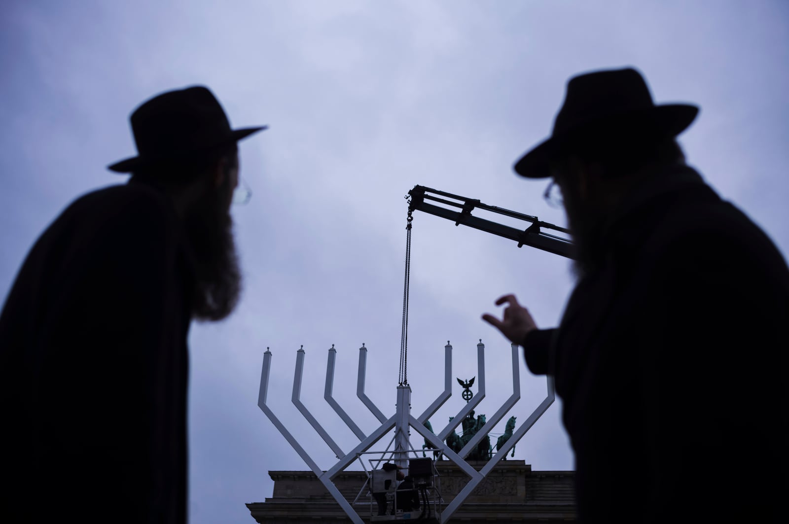 Rabbi Yehuda Teichtal, right, and Rabbi Shmuel Segal, left, watch the set-up of a giant Hanukkah Menorah by the Jewish Chabad Educational Center ahead of the Jewish Hanukkah holiday, in front of the Brandenburg Gate at the Pariser Platz in Berlin, Germany, Monday, Dec. 23, 2024. (AP Photo/Markus Schreiber)