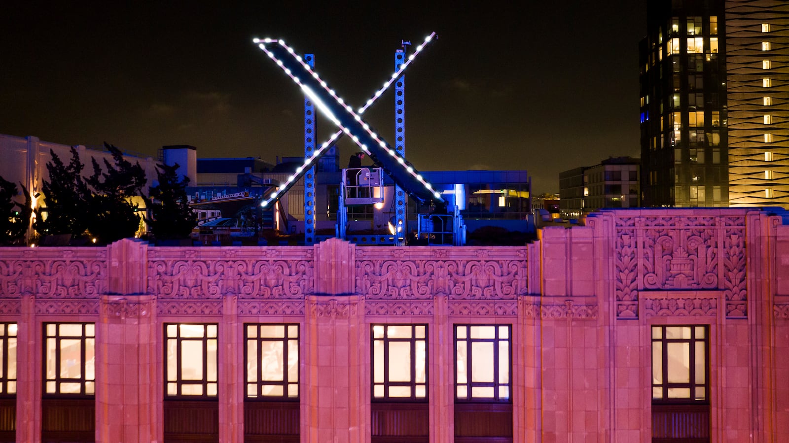 FILE - Workers install lighting on an "X" sign atop the company headquarters in downtown San Francisco, July 28, 2023. (AP Photo/Noah Berger, File)