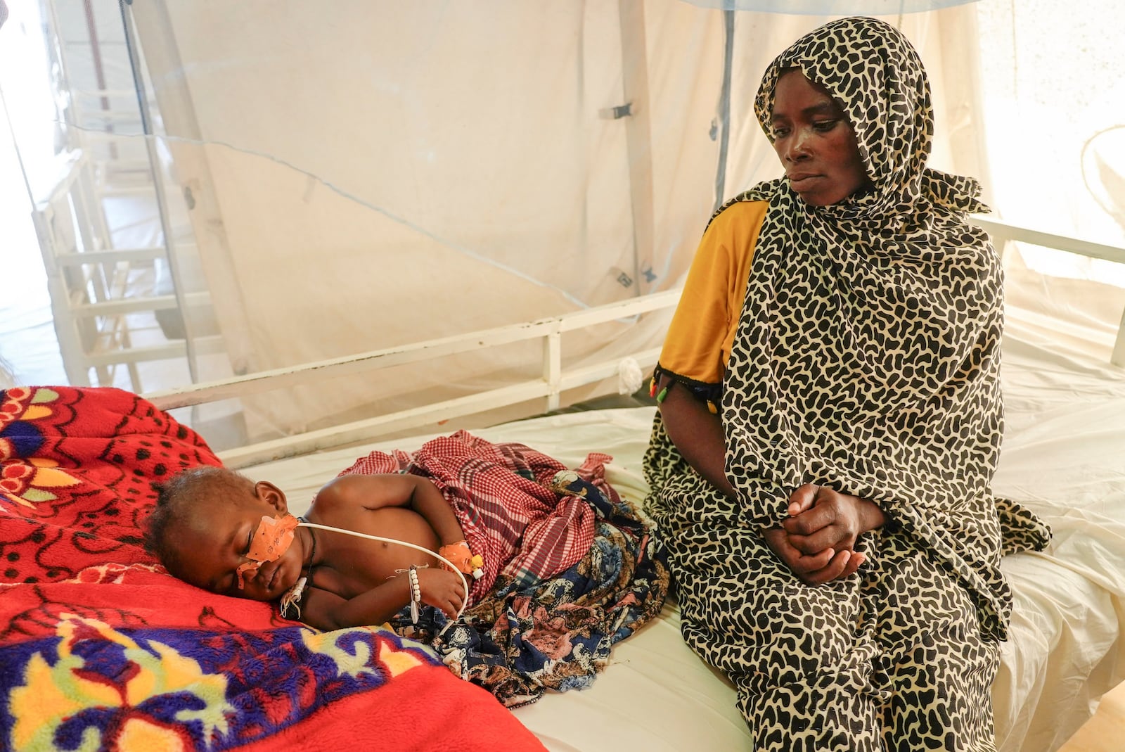 FILE - Sudanese Khadiga Omer adam sits by her sick child in an MSF-run clinic in the Aboutengue displacement site near Acre, Chad, Friday, Oct 4. 2024. (AP Photo/Sam Mednick, File)