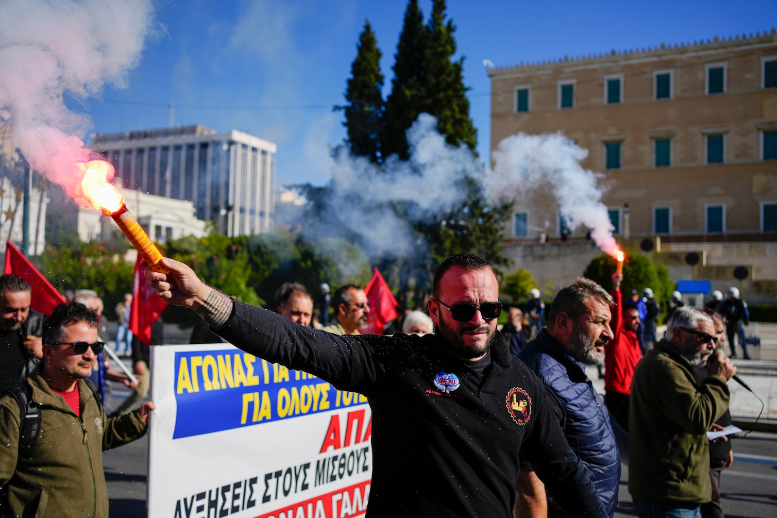 Protesters hold flares as they take part in rally, during a nationwide general strike organized by private and public sector unions demanding for better wages, in Athens, Greece, Wednesday, Nov. 20, 2024. (AP Photo/Thanassis Stavrakis)