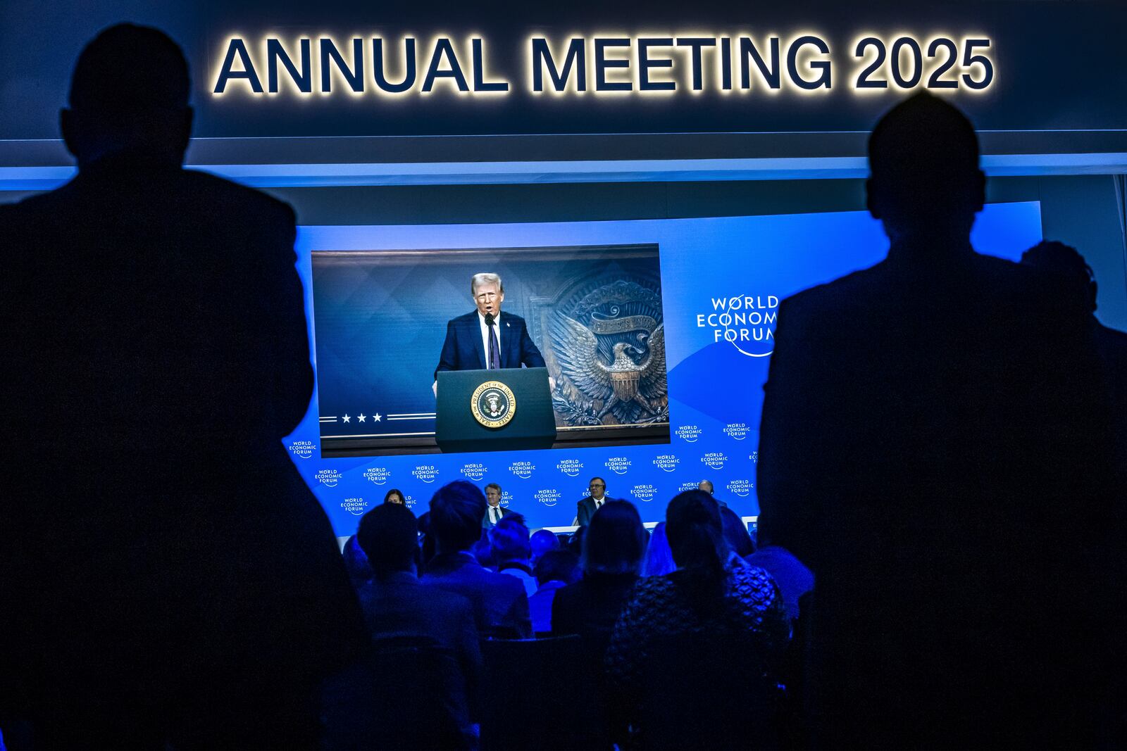 US President Donald J. Trump is shown on screens as he addresses via remote connection a plenary session in the Congress Hall, during the 55th annual meeting of the World Economic Forum (WEF), in Davos, Switzerland, Thursday, Jan. 23, 2025. (Michael Buholzer/Keystone via AP)