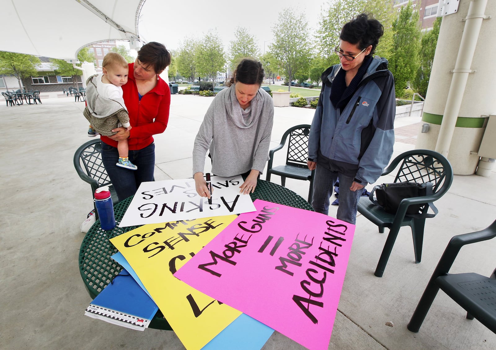 Elizabeth Herr, holding daughter Ann, 1, along with Erin Holscher Almazan, center, and Colleen Kelsey, right, participated in a local observance of the Million Mom March last May in Dayton. A new gun law set to take effect in Ohio will allow CCW permit-holder to bring guns to work as long as they are locked up in their personal cars. CHRIS STEWART / STAFF