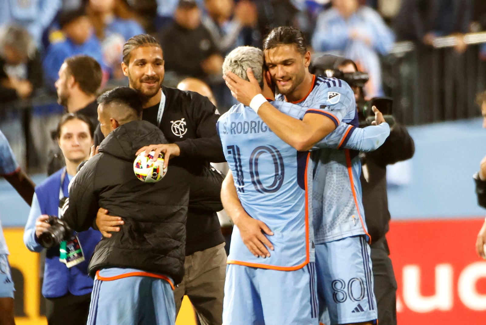 New York City FC's Santiago Rodriguez (10) embraces Justin Haak (80) after they defeated FC Cincinnati in Game 2 in the first round of the MLS Cup soccer playoffs, Saturday, Nov. 2, 2024, in New York. (AP Photo/Kena Betancur)