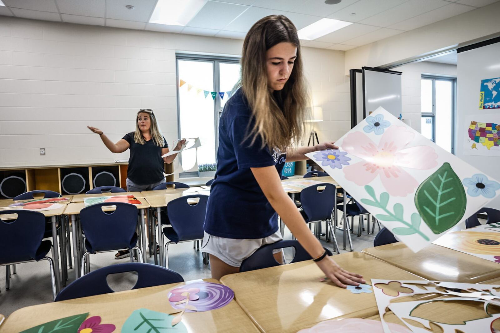 Kilee Johnson works on decorations for teacher Hannah Ross, in the background, at Fairborn Intermediate School. Ross is getting ready for the new school year. JIM NOELKER/STAFF