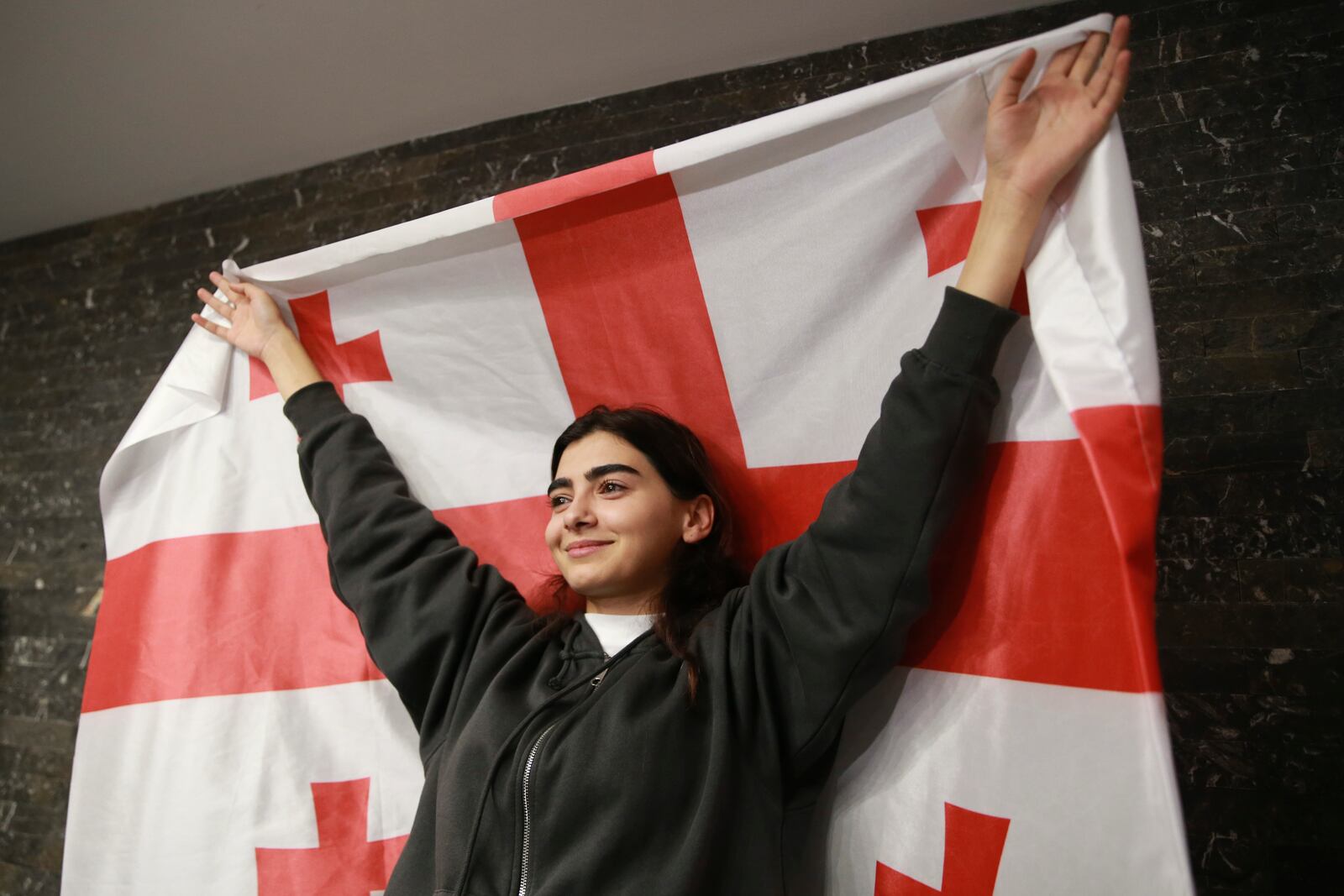 A supporter of the Coalition for Change holds a Georgian flag at coalition's headquarters after polls closing at the parliamentary election in Tbilisi, Georgia, Saturday, Oct. 26, 2024. (AP Photo/Zurab Tsertsvadze)