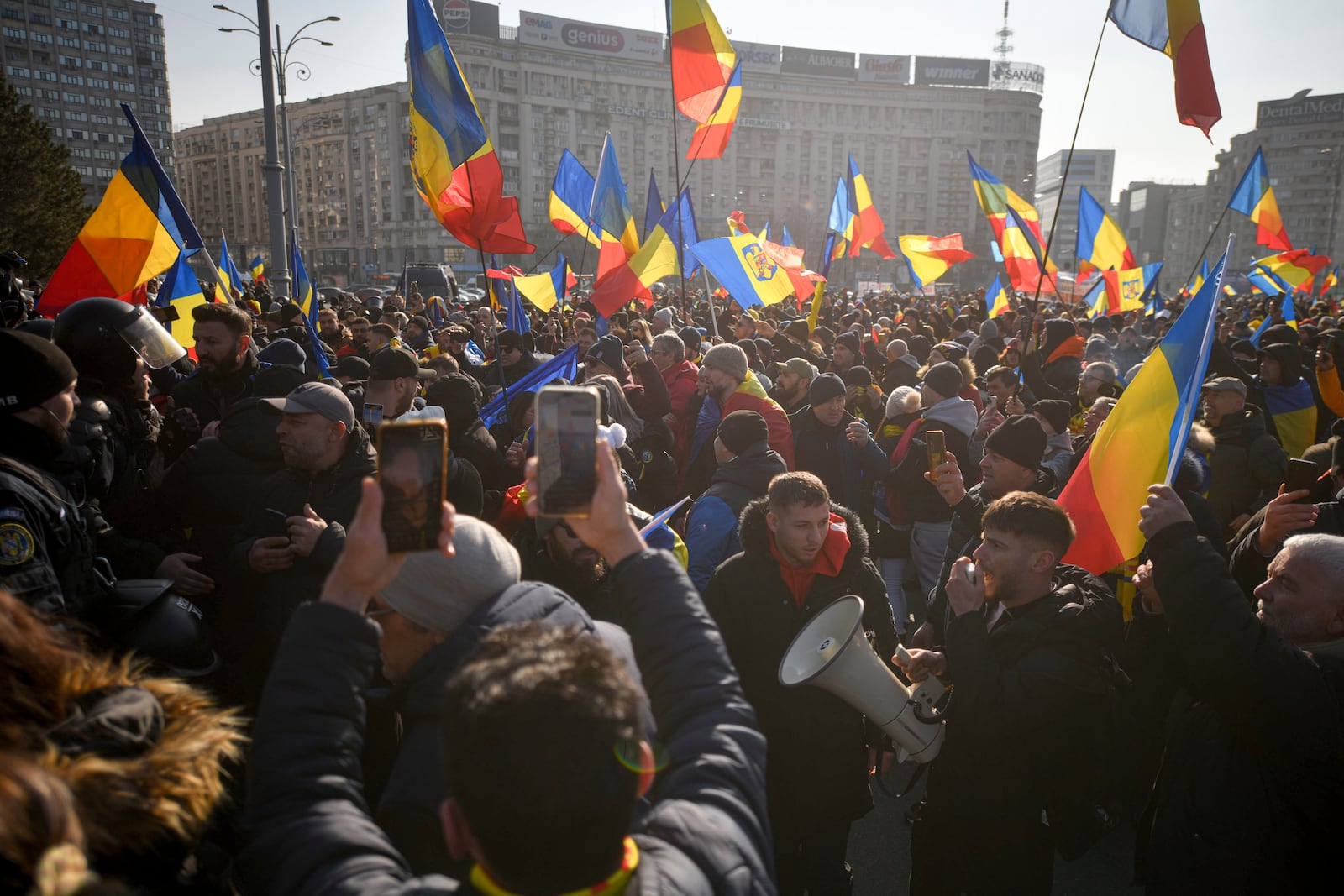 Supporters of Calin Georgescu, the winner of Romania's first round of presidential elections, wave flags and chant slogans in front of the government headquarters, in Bucharest, Romania, Monday, Feb. 10, 2025. (AP Photo/Alexandru Dobre)