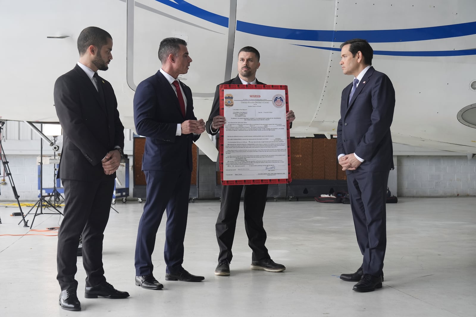 U.S. Secretary of State Marco Rubio, right, listens to Edwin F. Lopez, the attaché for DHS Homeland Security Investigations, second from left, next to the Venezuelan government airplane that Rubio announced is being seized by the U.S. during a news conference at La Isabela International Airport in Santo Domingo, Dominican Republic, Thursday, Feb. 6, 2025. At left is Dominican Public Prosecutor Enmanuel Ramirez, and holding the "seized" sign is Robert Cunniff from the U.S. Department of Commerce. (AP Photo/Mark Schiefelbein, Pool)