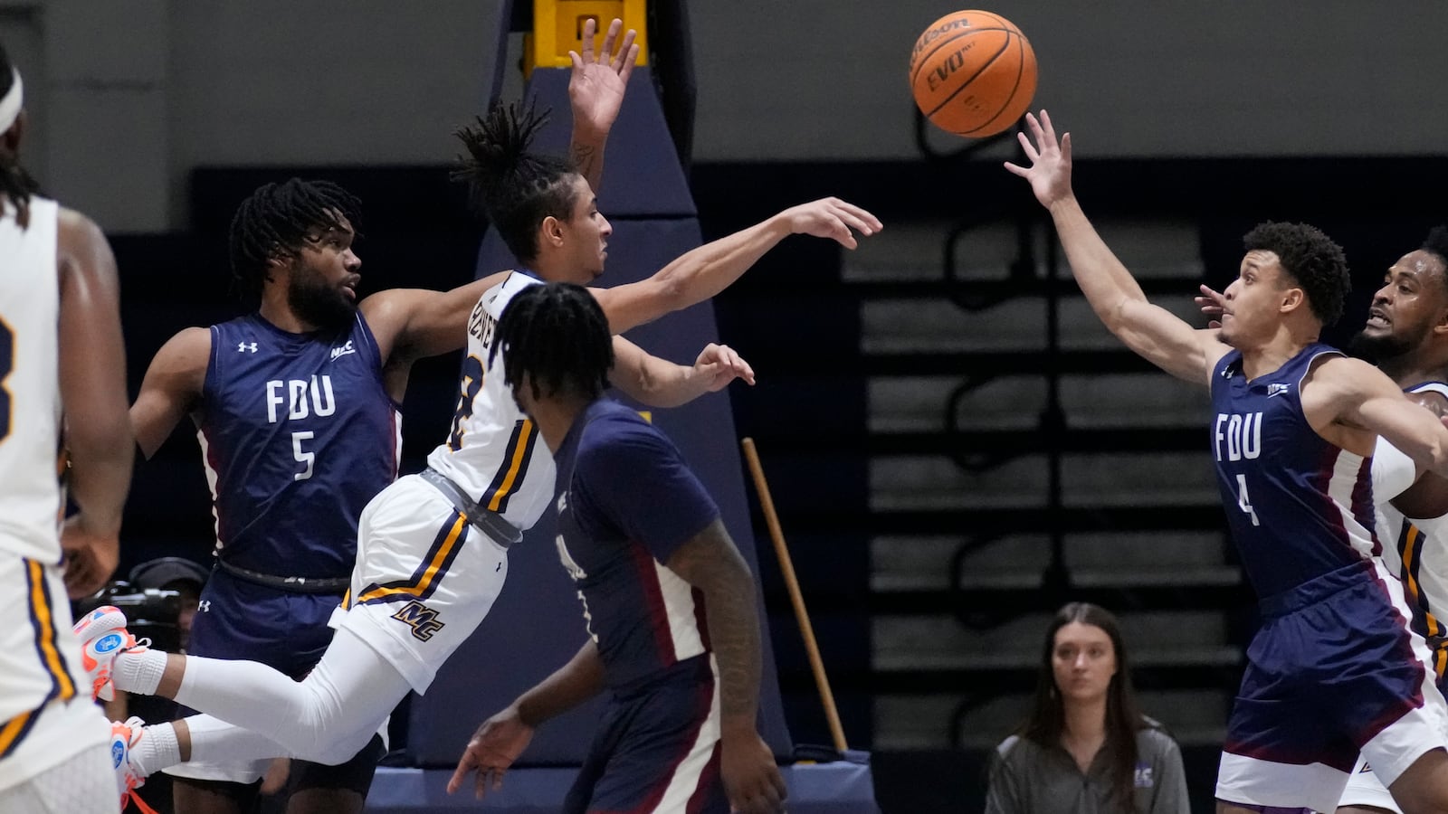 Merrimack guard Javon Bennett, center, passes the ball while pressured by Fairleigh Dickinson's Ansley Almonor (5) and Grant Singleton (4) during the first half of Northeast Conference men's NCAA basketball championship game, Tuesday, March 7, 2023, in North Andover, Mass. (AP Photo/Charles Krupa)