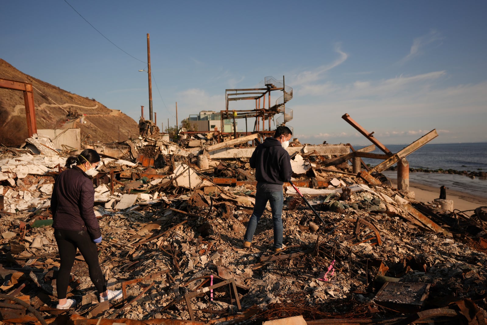 Tony Lai, center, rakes through the remains of his fire-ravaged beachfront property with his wife Everlyn in the aftermath of the Palisades Fire Tuesday, Jan. 28, 2025 in Malibu, Calif. (AP Photo/Jae C. Hong)