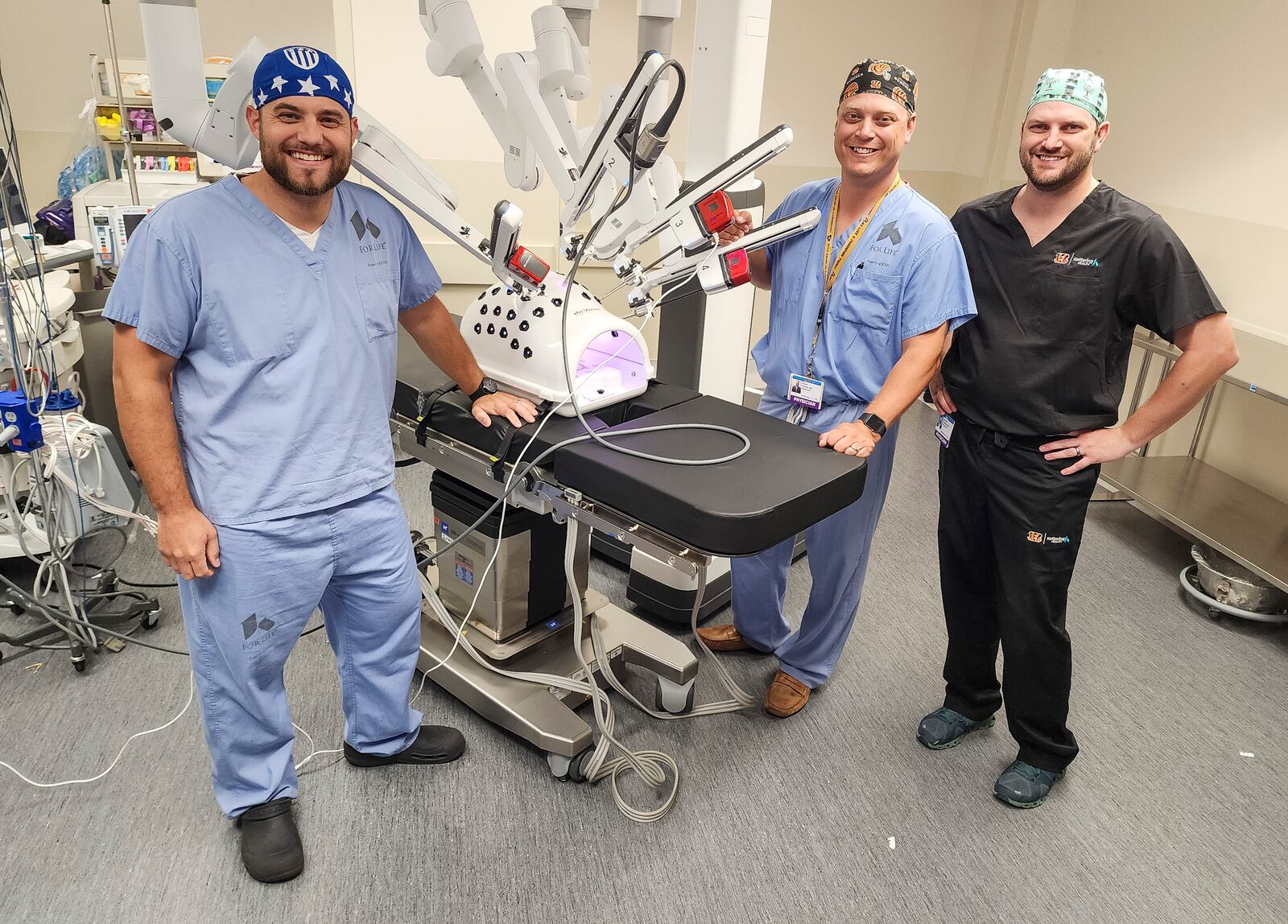 Kettering Health general surgeons Andrew Lichter, left, Ryan Grote, middle, and minimally invasive surgeon James Parker stand in front of the hospital's Davinci robot. Kettering Health Hamilton has been using their Davinci XI surgical robot. The hospital has multiple doctors, nurses and support staff trained in using the machine for less invasive surgeries with faster recovery time. NICK GRAHAM/STAFF