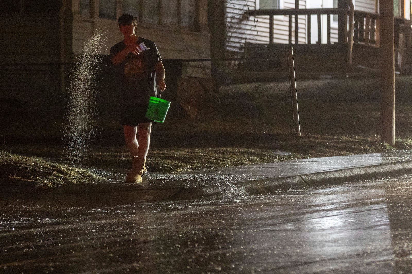 A man spreads salt on 42nd Street near Pacific Street after freezing rain coated surfaces with ice in Omaha, Neb. on Friday, Dec. 13, 2024. (Chris Machian/Omaha World-Herald via AP)