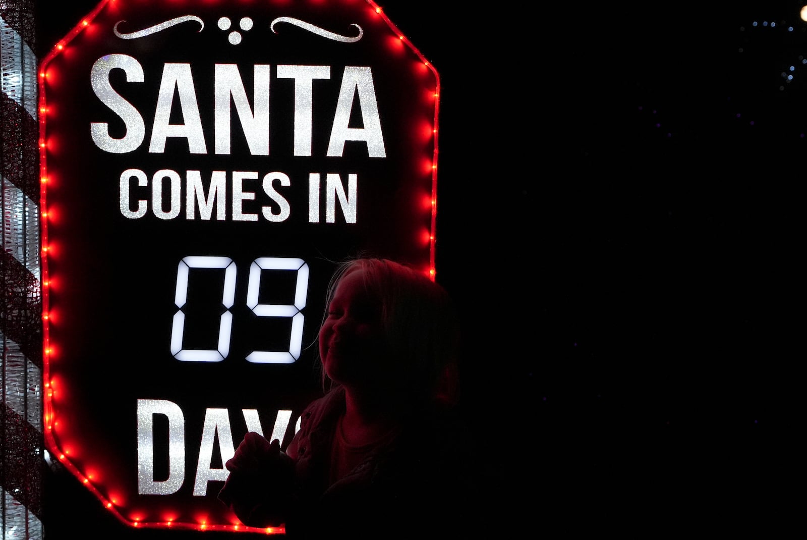 A child shows excitement at a sign that says "Santa Comes in Nine Days" at the Lights of Joy display Monday, Dec. 16, 2024, in Kennesaw, Ga. (AP Photo/Brynn Anderson)