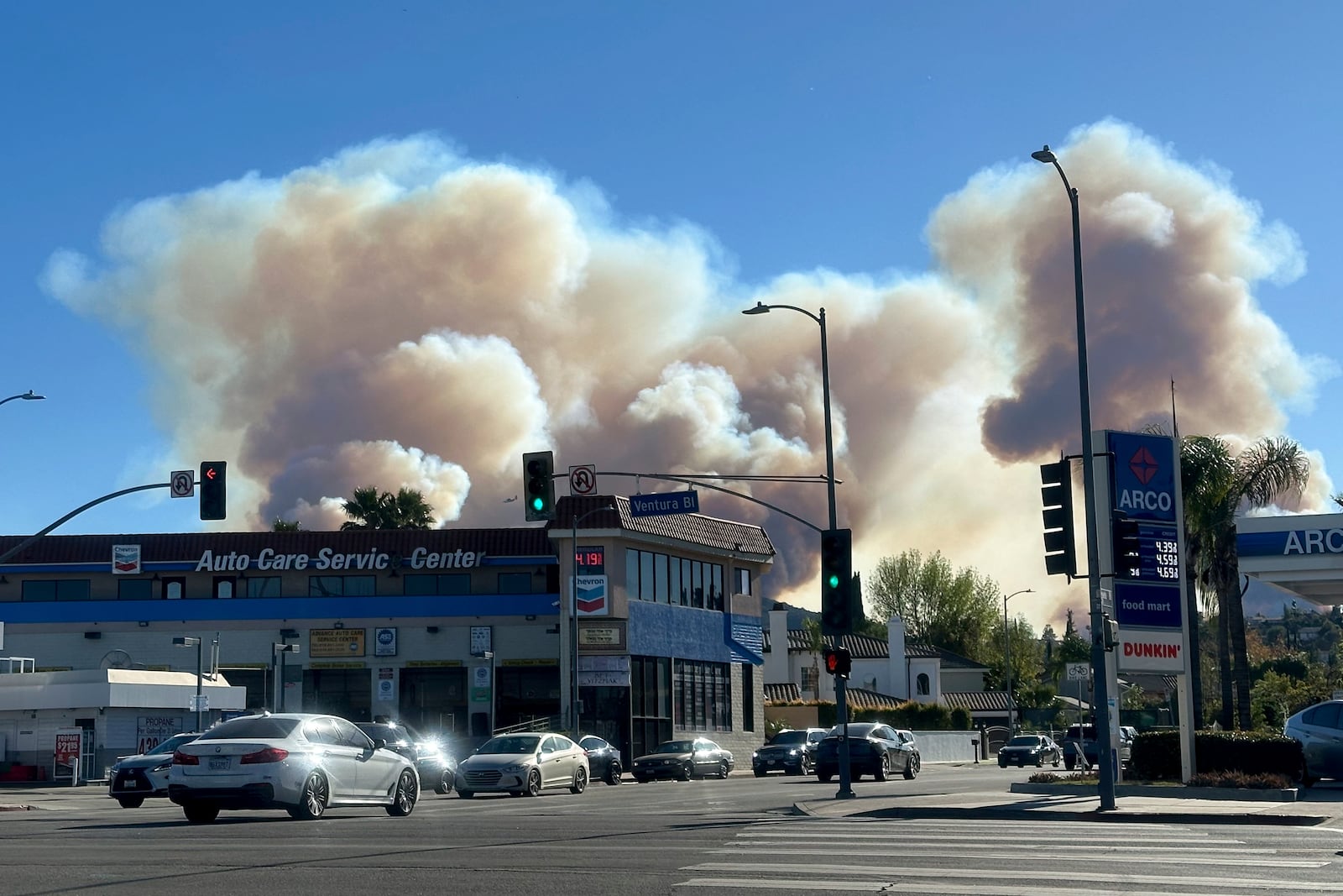 A plume of smoke from the Palisades Fire rises over Ventura Blvd. in the Woodland Hills section of Los Angeles, Friday, Jan. 10, 2025. (AP Photo/Greg Beacham)