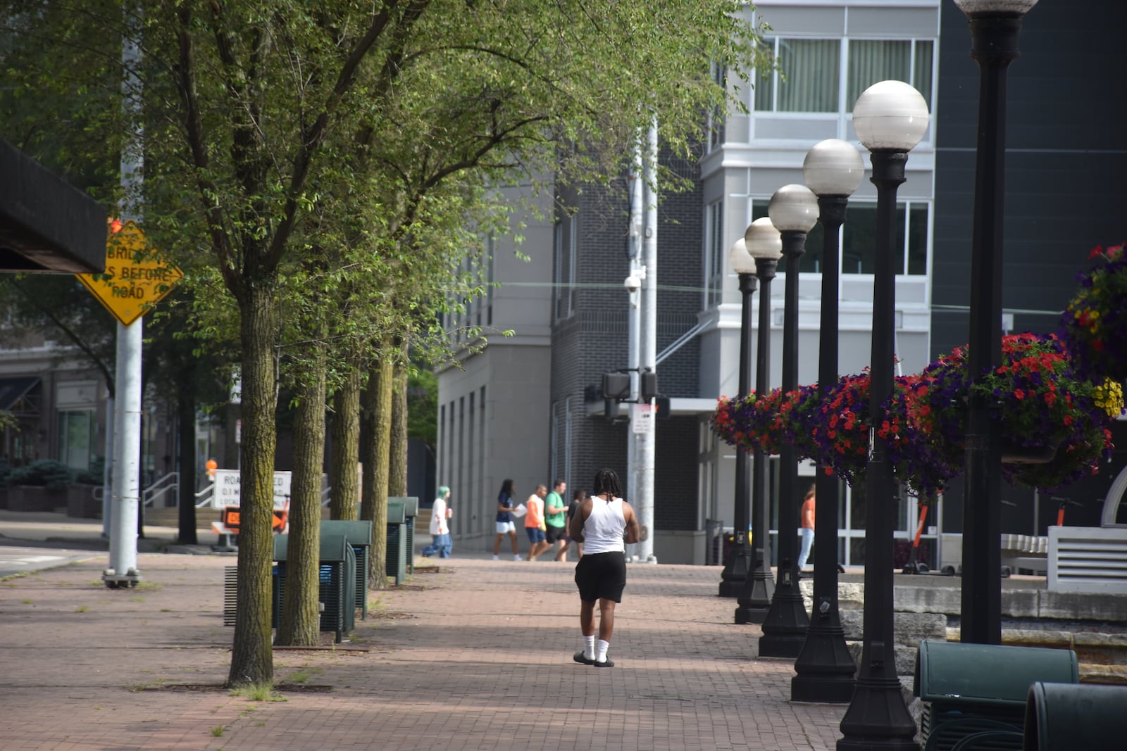 A man walks by a row of trees on Patterson Boulevard in downtown Dayton near Day Air Ball Park. CORNELIUS FROLIK / STAFF