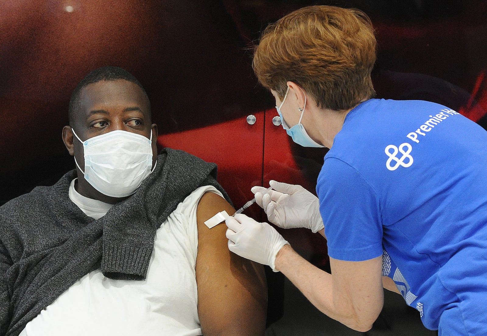 Premier Health administer its 100,000th dose of the COVID-19 vaccine to Tom Long, during a clinic at the University of Dayton Arena. MARSHALL GORBY\STAFF