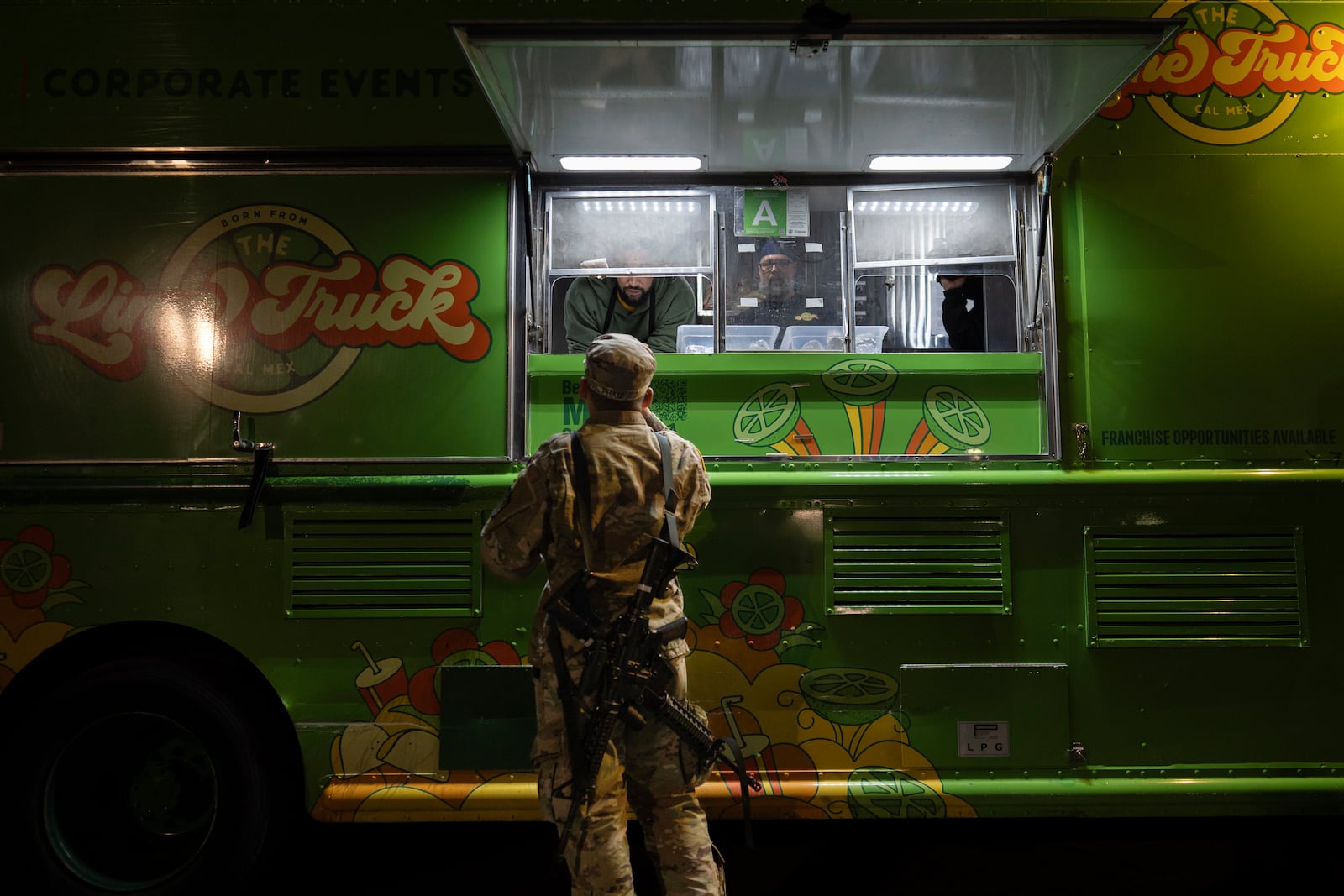 World Central Kitchen Chef Corp member Daniel Shemtob, upper left, and Benton Atkisson, right, serve a member of the California National Guard from his food truck, The Lime Truck, as he hands out burritos to Eaton Fire first responders at the Rose Bowl Stadium, Wednesday, Jan. 15, 2025, in Pasadena, Calif. (AP Photo/Carolyn Kaster)