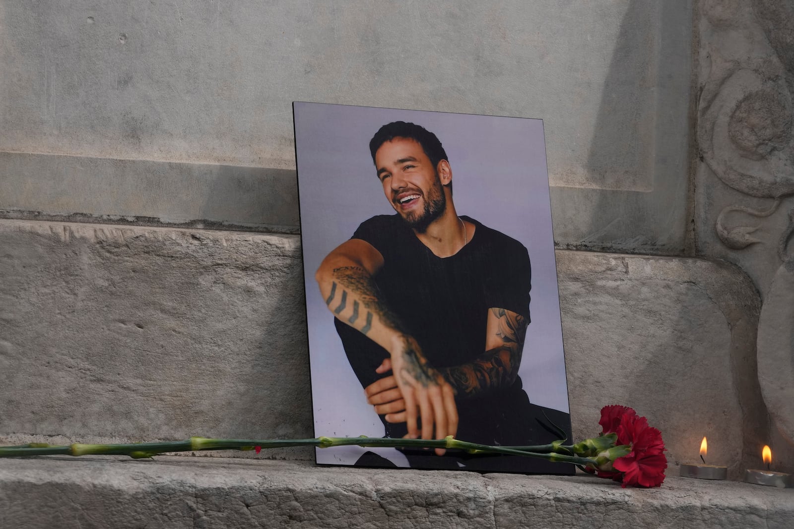 A photo of former One Direction singer Liam Payne is placed with a rose and candles as fans gather in Madrid, Spain, Sunday, Oct. 20, 2024, after the British pop singer fell to his death from a hotel balcony in Argentina. (AP Photo/Paul White)