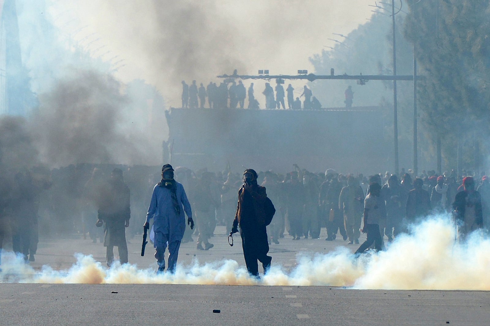 Supporters of imprisoned former premier Imran Khan's Pakistan Tehreek-e-Insaf party, throw stones after police officers fired tear gas shells to disperse them during clashes, in Islamabad, Pakistan, Tuesday, Nov. 26, 2024. (AP Photo/Irtisham Ahmed)