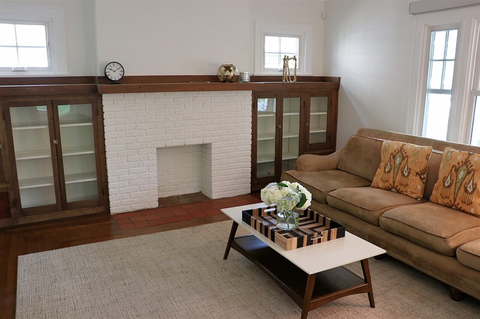 Tall French doors open from the dining room into the front living room, which has the original brick fireplace and brick hearth. 