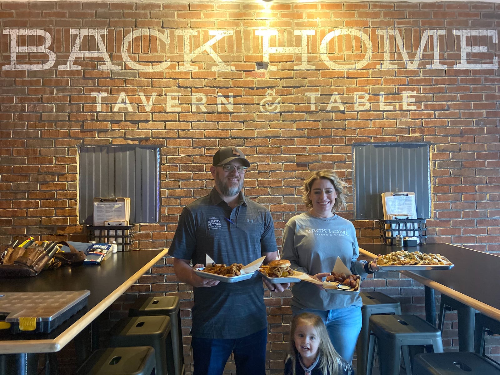 Two of the restaurant's owners, Jason and Michelle Dobbin are pictured here holding some of Back Home Tavern & Table's specialty dishes, with their daughter Taylor. ALLEGRA CZERWINSKI / STAFF PHOTO