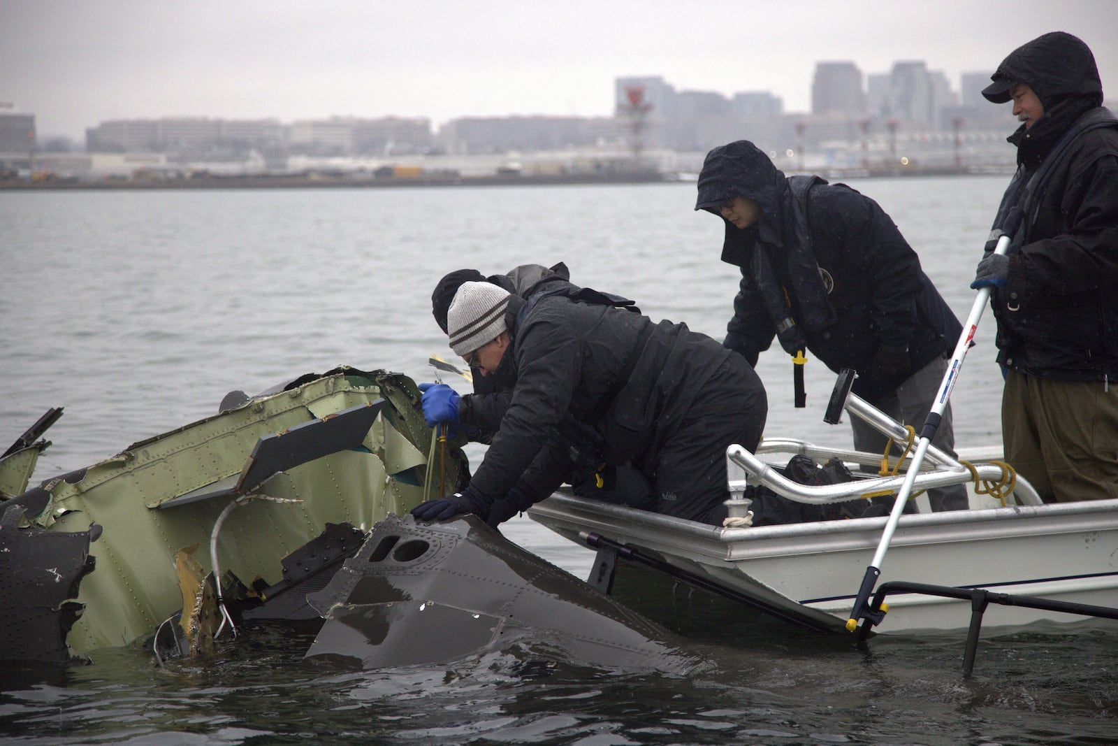 In this undated image provided by the National Transportation Safety Board, NTSB investigators and members of the salvage crew recover wreckage from the Army Black Hawk helicopter that collided with an American Airlines jet Wednesday night, Jan. 29, 2025, near Ronald Reagan Washington National Airport in Arlington, Va. (NTSB via AP)