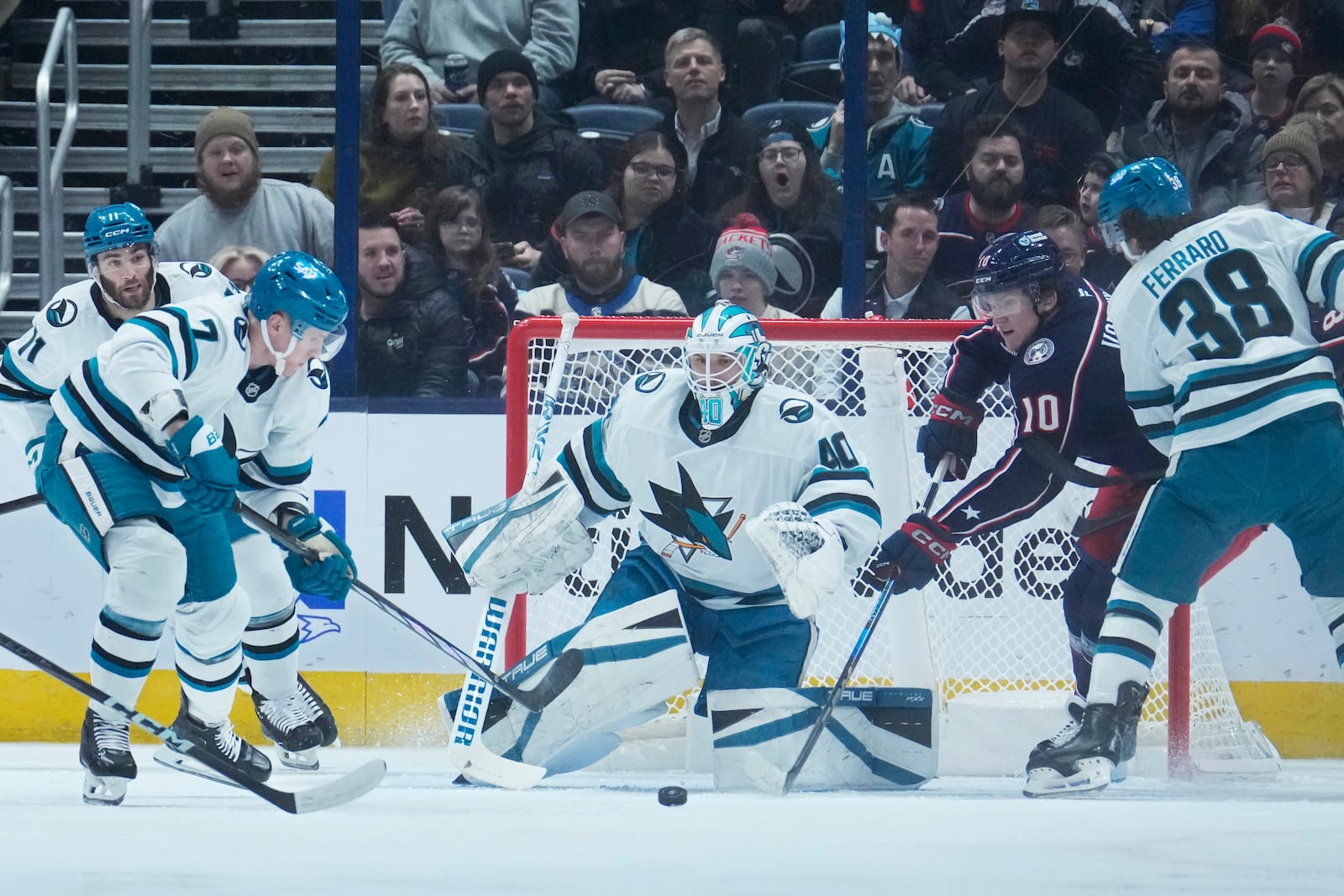 San Jose Sharks center Nico Sturm (7) and Columbus Blue Jackets left wing Dmitri Voronkov (10) reach for the puck in front of goaltender Alexandar Georgiev (40) in the first period of an NHL hockey game Thursday, Jan. 16, 2025, in Columbus, Ohio. (AP Photo/Sue Ogrocki)