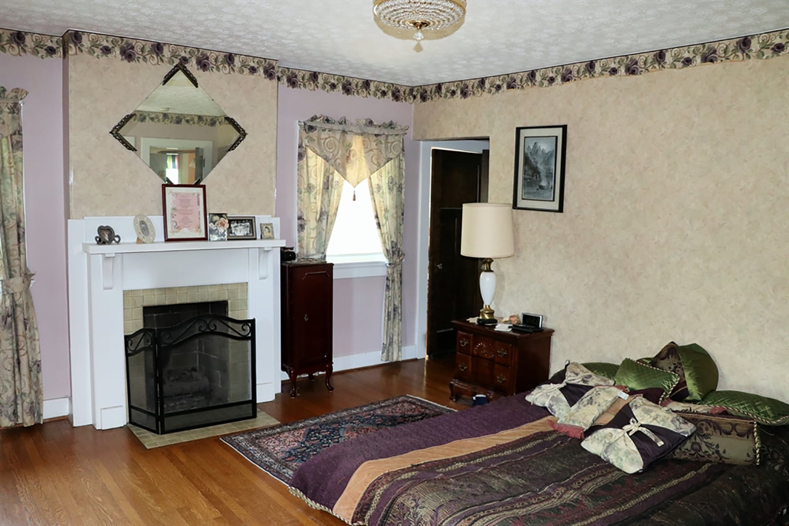 The main bedroom has a fireplace with wood mantel and three large windows. CONTRIBUTED PHOTO BY KATHY TYLER