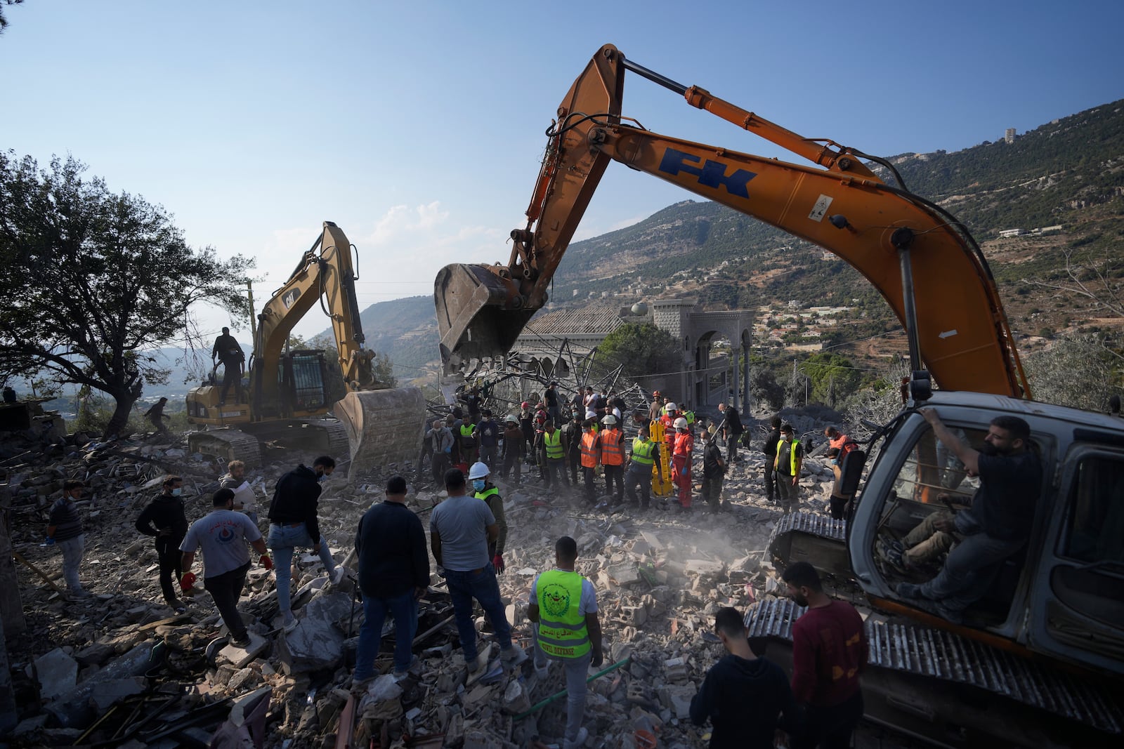 Rescue workers use excavators to remove the rubble of a destroyed house hit in an Israeli airstrike, as they search for victims in Aalmat village, northern Lebanon, Sunday, Nov. 10, 2024. (AP Photo/Hassan Ammar)