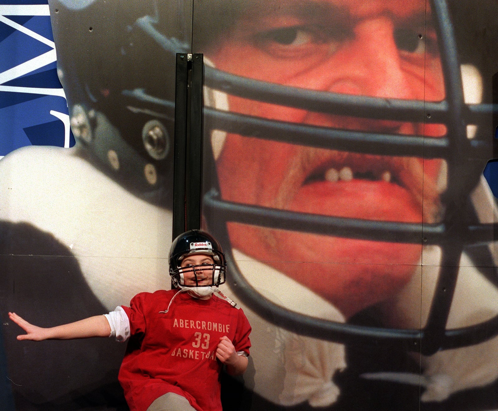 000128. ATLANTA. John Prescott, 12, of Covington poses for his parents in front of a picture of former NFL great Jack Lambert at the NFL Experience on Friday, 1/28/00. RICH ADDICKS/STAFF