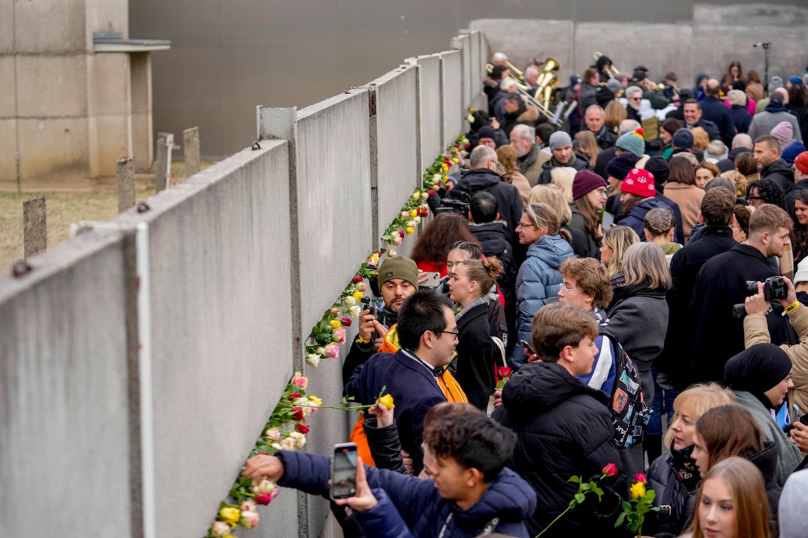 People attend a flower laying ceremony on occasion of the 35th wall anniversary at the grounds of the Berlin Wall Memorial, Berlin, Germany, Saturday, Nov.9, 2024. (AP Photo/Ebrahim Noroozi)