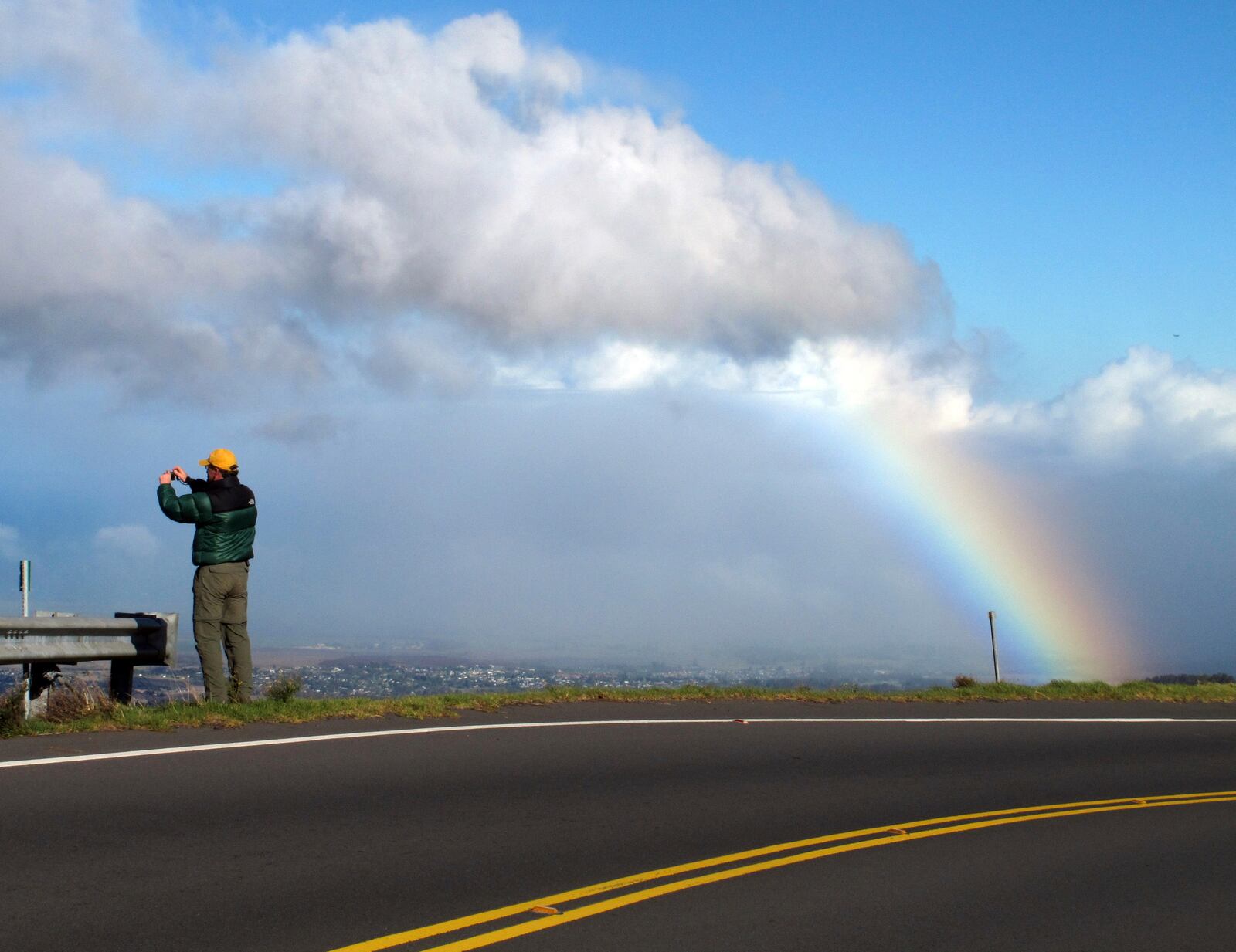 FILE - A tourist takes photos of a rainbow on the road that leads to Haleakala National Park on the Hawaiian island of Maui, Dec. 19, 2012. (AP Photo/Martha Irvine, File)