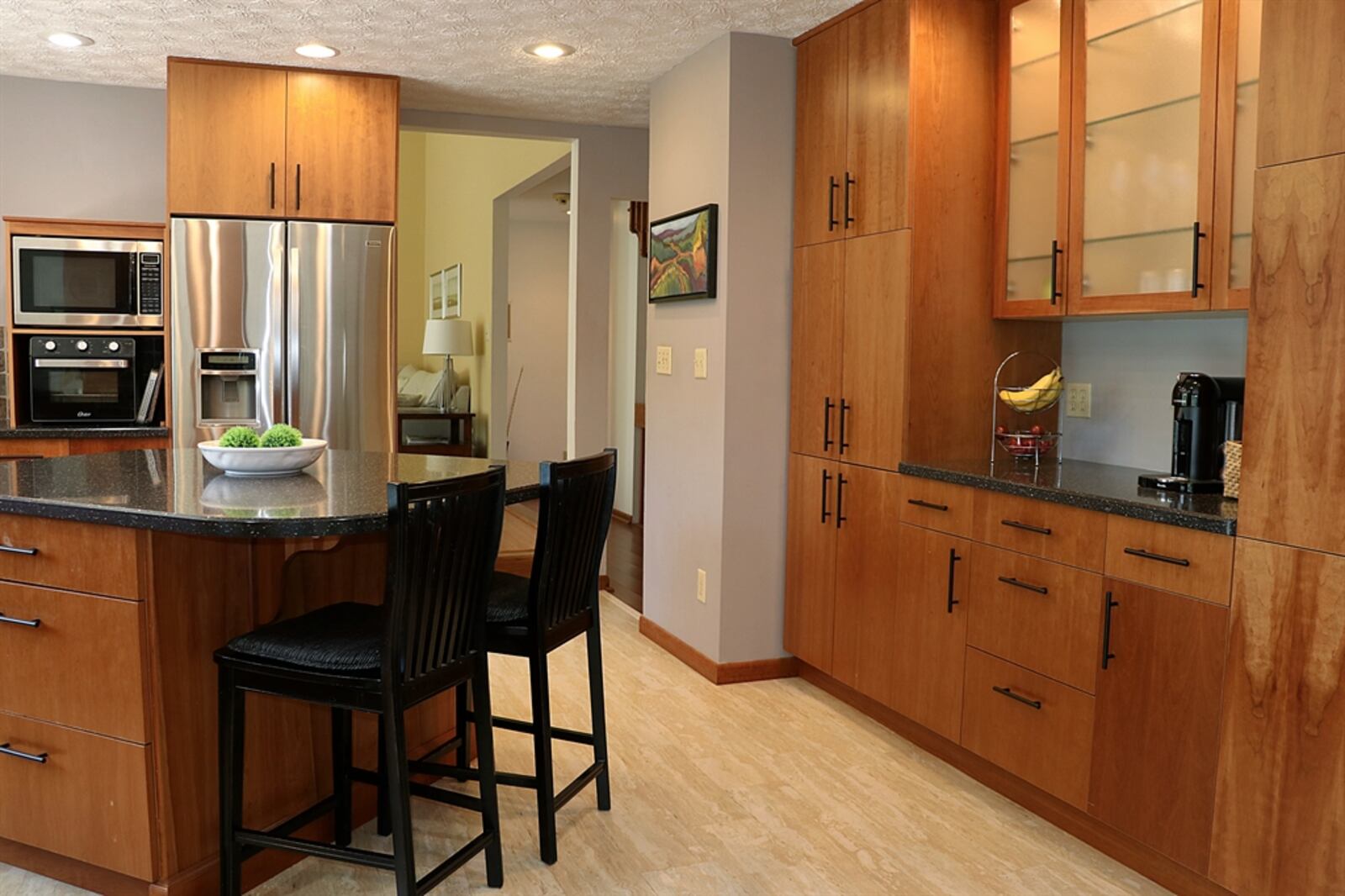 An island has an extended counter to allow breakfast bar seating for up to four and hanging lights highlight the additional preparation counter space.