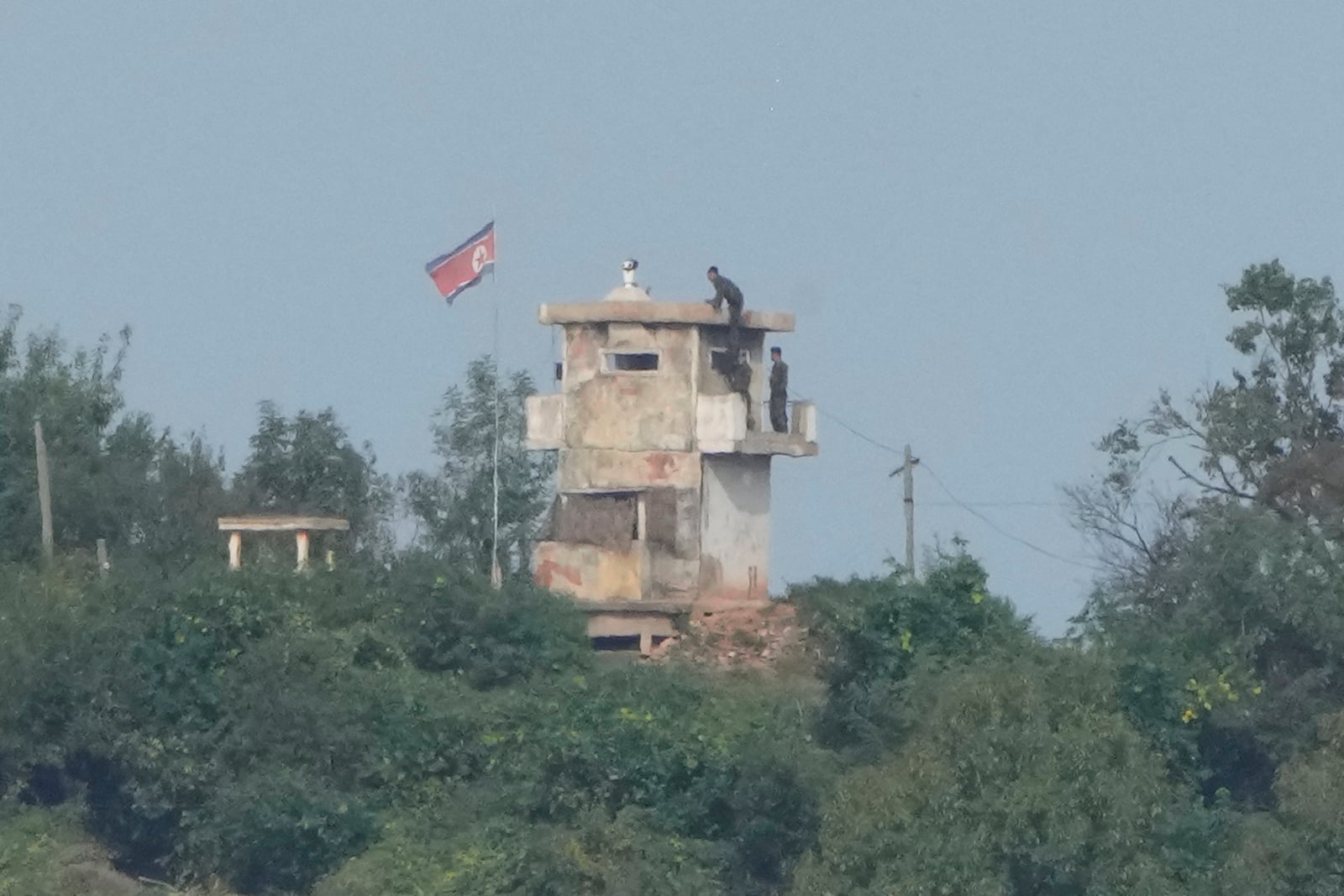 FILE - North Korean soldiers work at the North's military guard post as a North Korean flag flutters in the wind, are seen from Paju, South Korea, near the border with North Korea, Thursday, Oct. 10, 2024. (AP Photo/Ahn Young-joon, File)